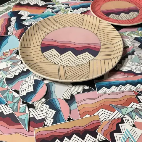 Cut ceramic decals with a fired plate showing the final applied result