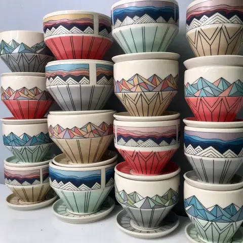 Stacked finished ceramic bowls and cups decorated with custom decals